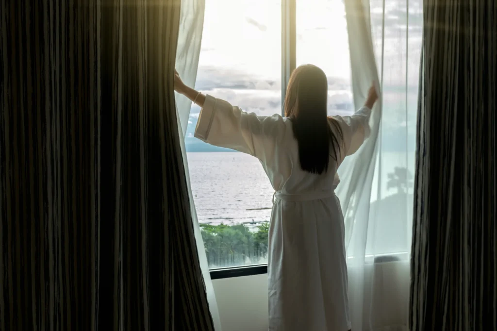 Réveil dans une chambre d’hôtel impeccable, peignoir blanc face à la mer — propreté hôtelière SA Clean