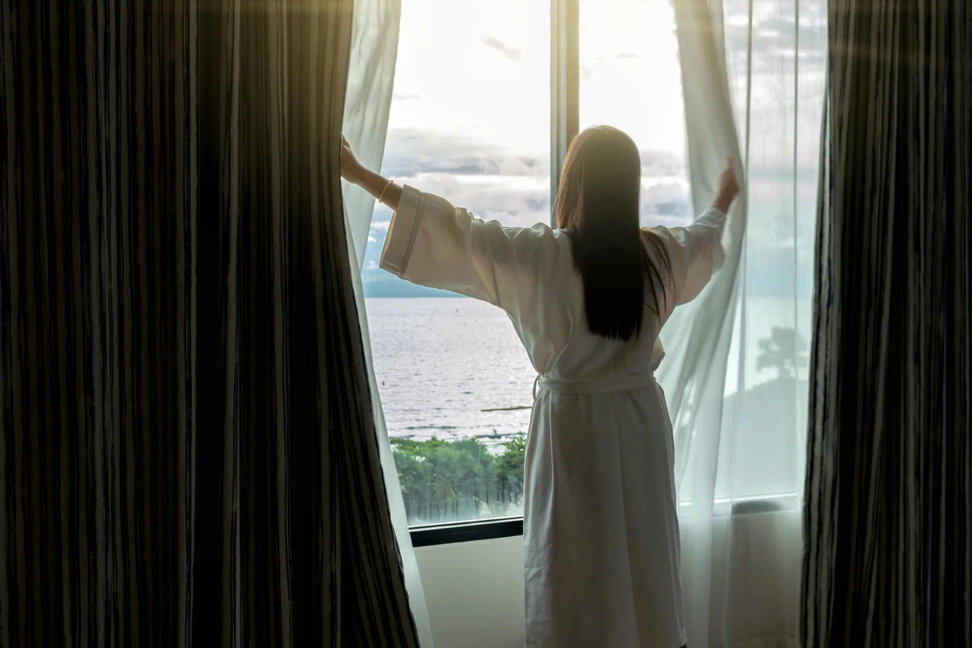 Réveil dans une chambre d’hôtel impeccable, peignoir blanc face à la mer — propreté hôtelière SA Clean